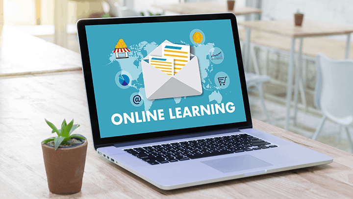 A person studying on a laptop, surrounded by books and educational materials, representing online learning.